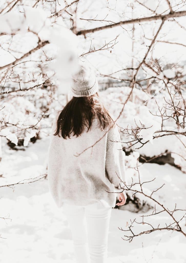 a snowy winter scene with a woman wearing a hat and jumper