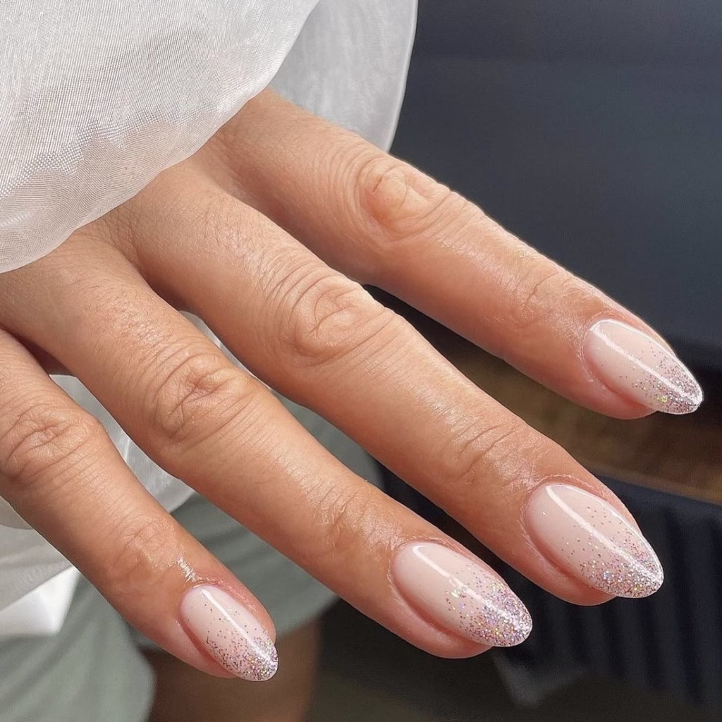 Sheer pink Christmas nails with fine silver glitter for a frosty effect.